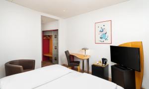 a hotel room with a bed and a flat screen tv at Mainstreet Hotel in Dietzenbach