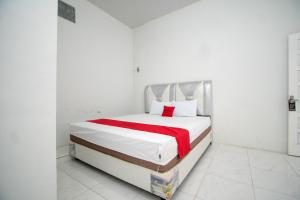 a white bedroom with a bed with a red blanket at RedDoorz Syariah near Danau Lut Tawar Takengon 2 in Takengon