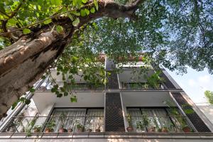 un edificio con un árbol delante de él en Bungalow 157 en Nueva Delhi