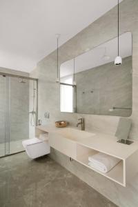 een badkamer met een wastafel, een toilet en een spiegel bij Bungalow 157 in New Delhi
