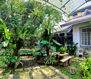 a garden with a bench and trees and a house at Auntie Gigi's Place in Tagaytay