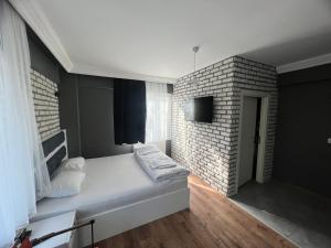 a bedroom with a white bed and a brick wall at Karaca Suite in Tuzla