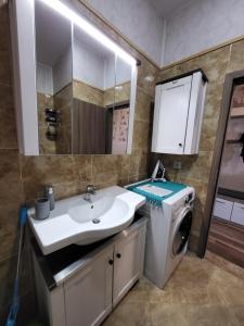 a bathroom with a sink and a washing machine at Lazuren Bryag Lux suite in Burgas City
