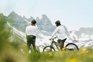 dos personas de pie en una montaña con sus bicicletas en Peaks Place Apartments & SPA, en Laax