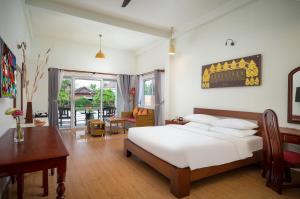 a bedroom with a bed and a desk and a table at Sala Siem Reap Hotel in Siem Reap