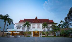 a large white building with palm trees in front of it at Sala Siem Reap Hotel in Siem Reap