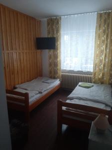 two beds in a small room with a window at Villa Centrum in Malbork
