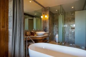 a bathroom with a tub and a sink and a mirror at Adiwana Bisma in Ubud