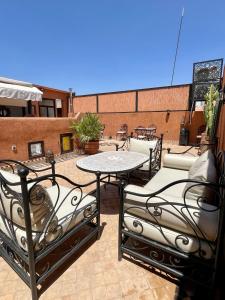 un patio con mesa y sillas en la azotea en Riad Jolie, en Marrakech