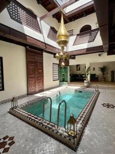 una piscina en un edificio con una lámpara de araña en Riad Jolie en Marrakech
