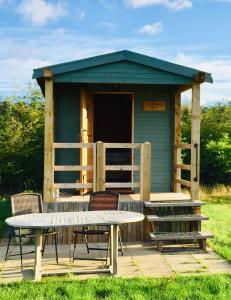 einem Picknicktisch und Stühlen vor einem Schuppen in der Unterkunft Woodman's Rest in Kirdford