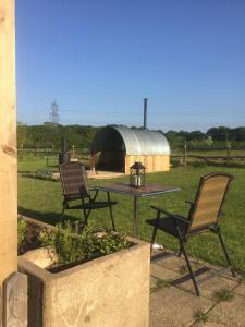 2 Stühle und ein Tisch in einem Hof mit einem Gebäude in der Unterkunft Woodman's Rest in Kirdford