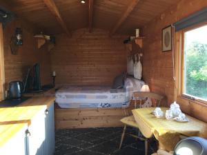 a bedroom with a bed in a wooden cabin at Woodman's Rest in Kirdford