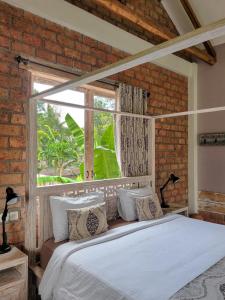 a bedroom with a white bed and a window at Les Rizieres Lombok - Tetebatu in Tetebatu