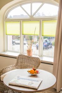 a table with a bowl of fruit on it in front of a window at Dünen Stuuv in Sankt Peter-Ording