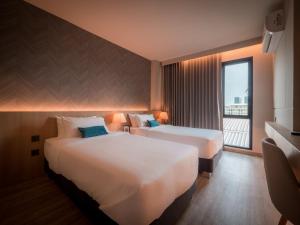 2 Betten in einem Hotelzimmer mit Fenster in der Unterkunft 56 Hotel in Bangna