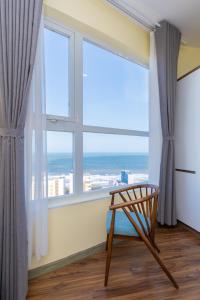 uma cadeira em frente a uma janela com vista para o oceano em Goldsea Vũng Tàu - Khang Apartment em Vung Tau