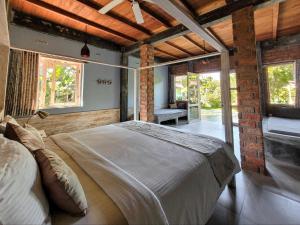 a bedroom with a large bed in a room with windows at Les Rizieres Lombok - Tetebatu in Tetebatu