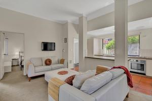 a living room with two white couches and a kitchen at Como Executive Apartment in Perth