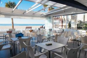 restauracja z białymi stołami i krzesłami oraz plaża w obiekcie Las Damas 10C w mieście Benidorm