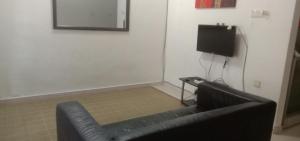 a black leather couch in a room with a television at Homestay Humair in Marang