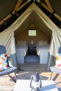 - une chambre dans une tente avec 2 lits et 2 chaises dans l'établissement Safaritent Lodge 2 (2 persoons), à Ruurlo