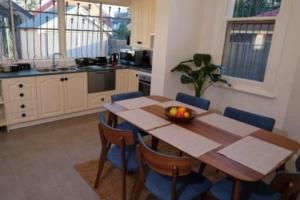 eine Küche mit einem Holztisch und blauen Stühlen in der Unterkunft Beautiful Cottage in cosmopolitan Norwood in Kensington and Norwood + 13 Fotos