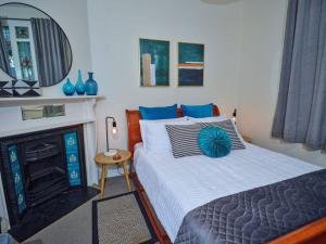 ein Schlafzimmer mit einem Bett und einem Kamin in der Unterkunft Beautiful Cottage in cosmopolitan Norwood in Kensington and Norwood