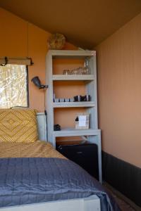 a bedroom with a bed and a book shelf at Safaritent Lodge 2 plus in Ruurlo