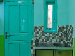 a kitchen with a green door and a sink at RedDoorz Syariah near Sunrise Mall Mojokerto in Mojokerto