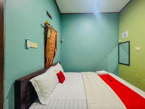 a bedroom with a bed with a red and white blanket at RedDoorz Syariah near Sunrise Mall Mojokerto in Mojokerto