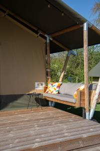 una cama bajo un dosel en una terraza de madera en Safaritent Lodge 5, en Ruurlo