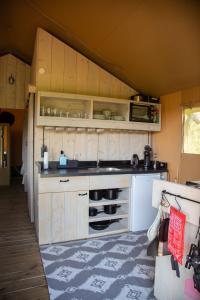 een kleine keuken met houten kasten en een tapijt bij Safaritent Lodge 5 in Ruurlo