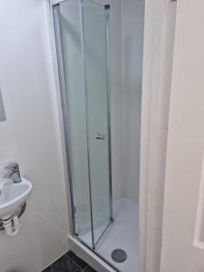 a shower with a glass door next to a sink at Dunkirk House in Southampton