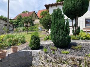 a garden with trees and bushes in front of a house at Ferienhaus Doris in Bad Urach