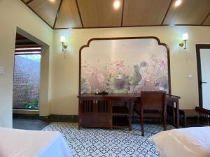 a bedroom with a desk and a wall with flowers at Le Jardin De Tam Coc in Ninh Binh