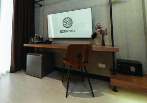 uma secretária com uma televisão e uma cadeira num quarto em EX2 Hotel em Ban Bang Khen (1)