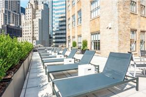 a row of chaise lounge chairs on the roof of a building at FiDi 2BR w Gym Lounge Complete Gym NYC-497 in New York