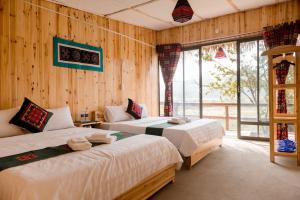 Le Chalet Homestay في ها باك: سريرين في غرفة بجدران خشبية ونوافذ