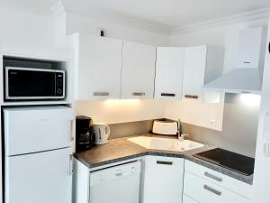 una cucina bianca con lavandino e forno a microonde di Sur le remblai des Sables comprenant 2 ch parking et piscine a Les Sables-dʼOlonne