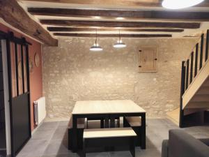 una mesa y un banco en una habitación con una pared de piedra en Maison de charme en Ligueil