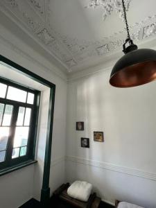 a room with a ceiling with a window and a lamp at Jugendstil Villa - 2 min zum Meer in Figueira da Foz