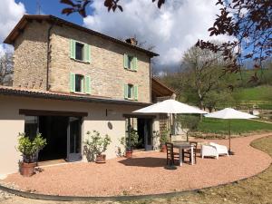 a house with two tables and umbrellas in front of it at Lo Smarrino agriturismo in Gubbio