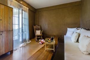 a bedroom with a bed and a chair and a window at Skopelos Holidays Hotel & Spa in Skopelos Town