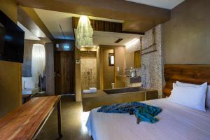 a bedroom with a bed and a bathroom with a tub at Skopelos Holidays Hotel & Spa in Skopelos Town