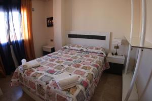 a bedroom with a bed with a quilt on it at Apartamentos Marina San Julian in Torrevieja