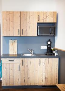 a kitchen with wooden cabinets and a sink and a microwave at Stadl Appartements in Türkheim