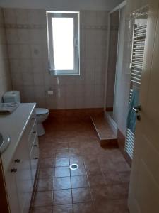 uma casa de banho com um chuveiro, um WC e uma janela. em Villa Calli em Malia