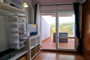 a room with a door to a balcony with a television at La Terracita del Bosque in El Bosque