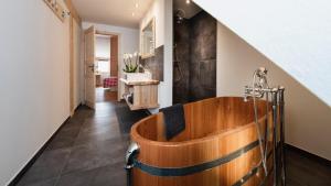 uma casa de banho com uma banheira de madeira no corredor em Gähwindehof Mountain Ranch Resort em Oberstaufen